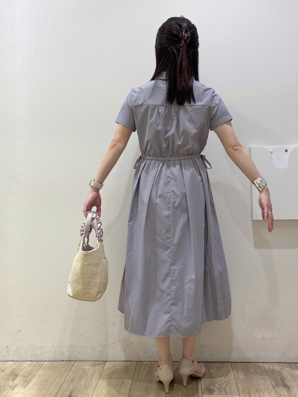 グレー系のワンピース、ベージュ系のトートバッグ、ベージュ系のパンプスを着用したレディースの春コーディネートの3枚目の写真