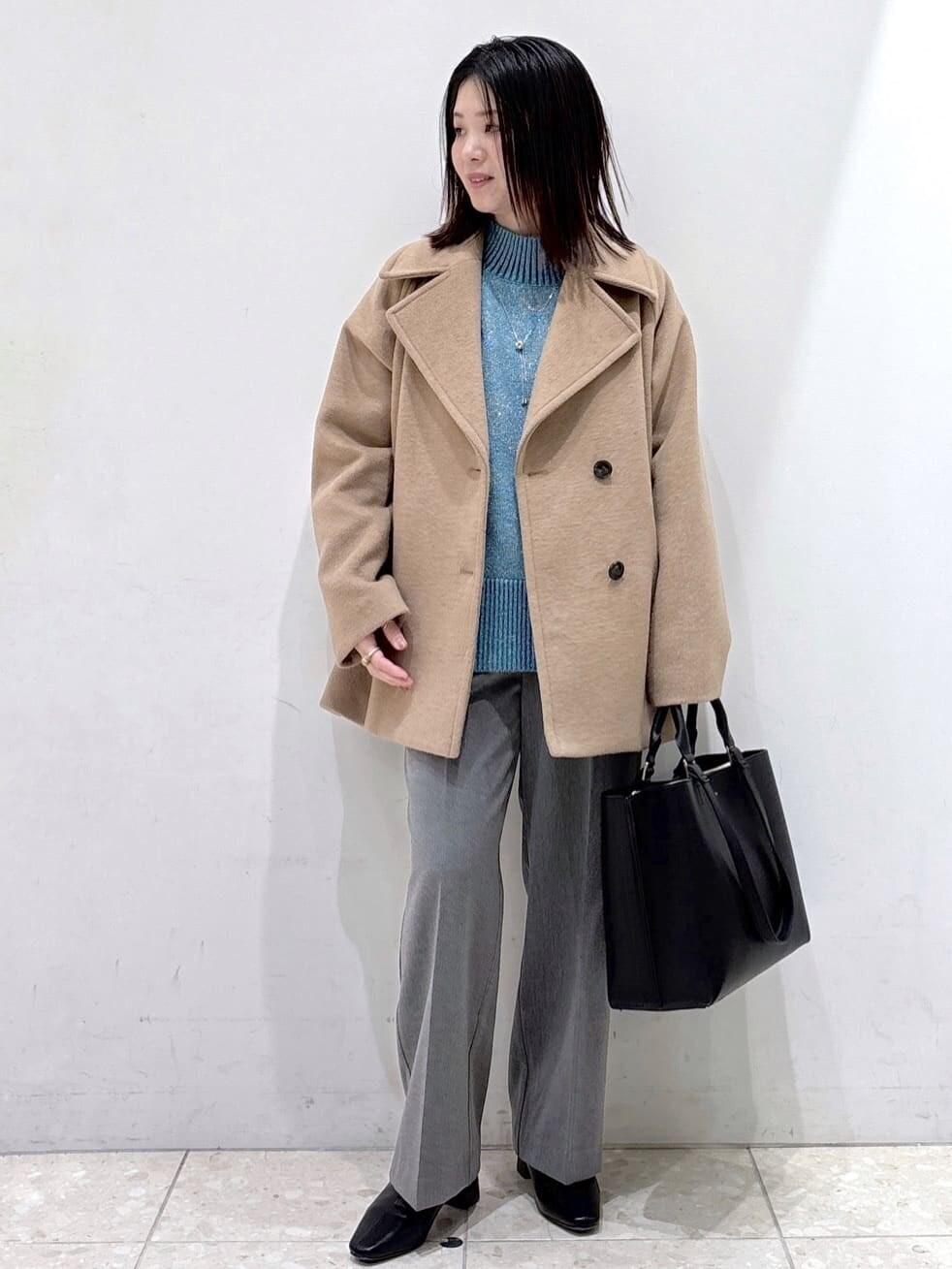 ブルー系のニット/セーター、グレー系のその他パンツ、ブラック系のトートバッグを着用したレディースの冬コーディネートの6枚目の写真