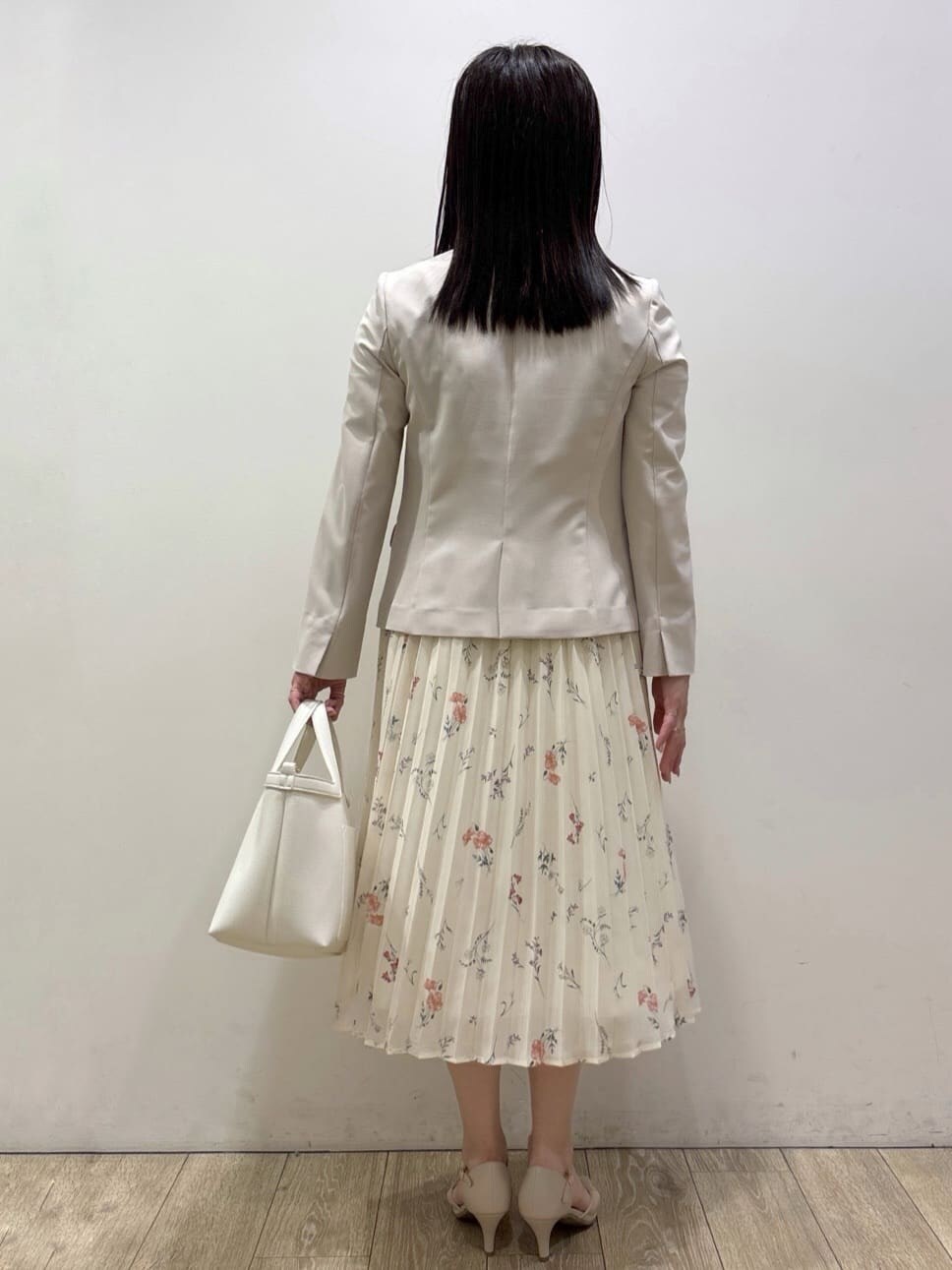 ベージュ系のノーカラージャケット、ベージュ系のパンプス、ホワイト系のショルダーバッグを着用したレディースの春コーディネートの3枚目の写真
