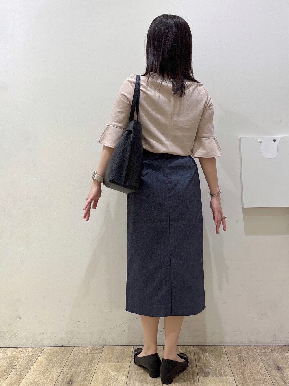 ブラック系のパンプス、ブラック系のトートバッグ、ブルー系のスカートを着用したレディースの春コーディネートの3枚目の写真