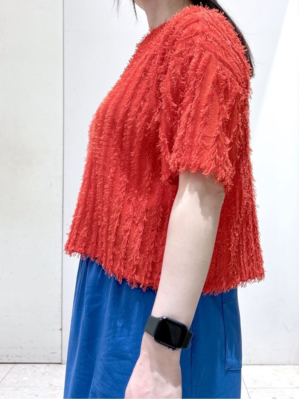 レッド系のニット/セーター、ブルー系のスカート、ベージュ系のトートバッグを着用したレディースの夏コーディネートの5枚目の写真