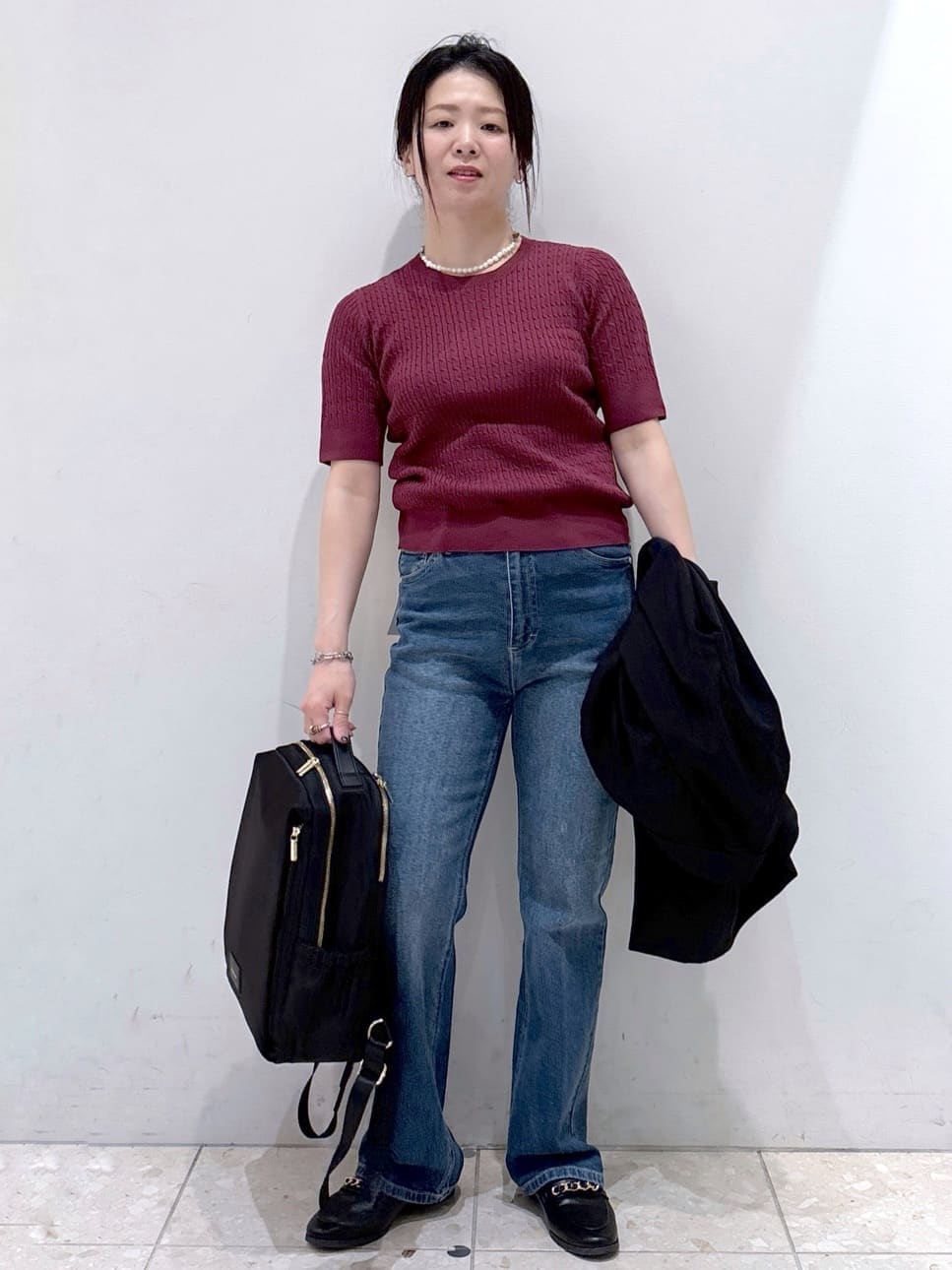 レッド系のニット/セーター、ブルー系のデニムパンツ、ブラック系のバックパック/リュックを着用したレディースの秋コーディネートの4枚目の写真