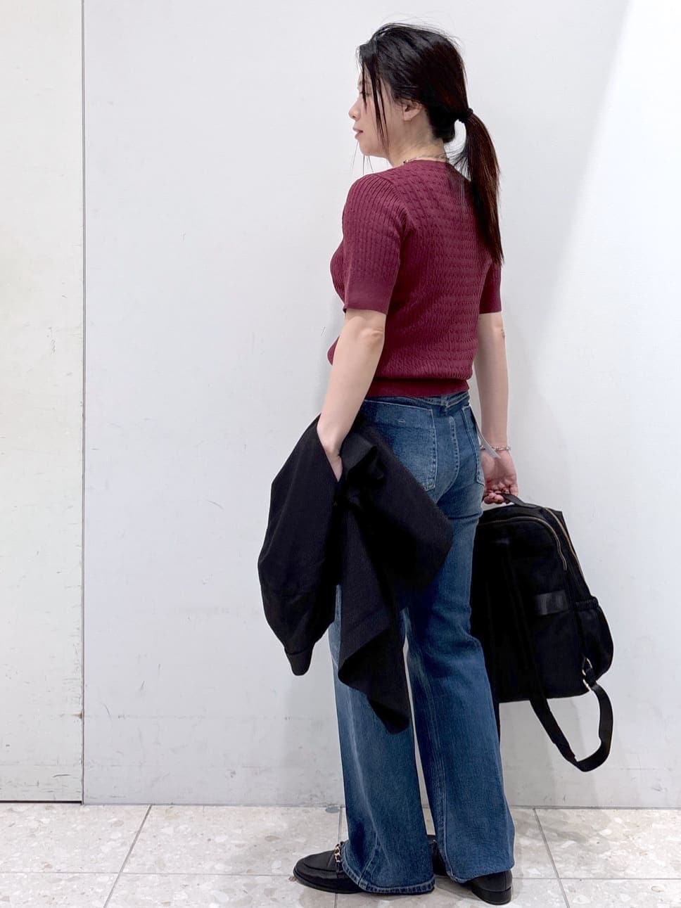 レッド系のニット/セーター、ブルー系のデニムパンツ、ブラック系のバックパック/リュックを着用したレディースの秋コーディネートの7枚目の写真