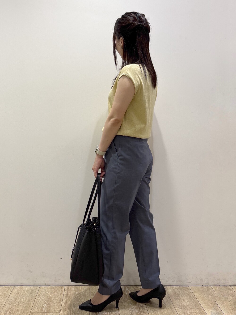 イエロー系のニット/セーター、グレー系のその他パンツ、ブラック系のトートバッグを着用したレディースの夏コーディネートの5枚目の写真