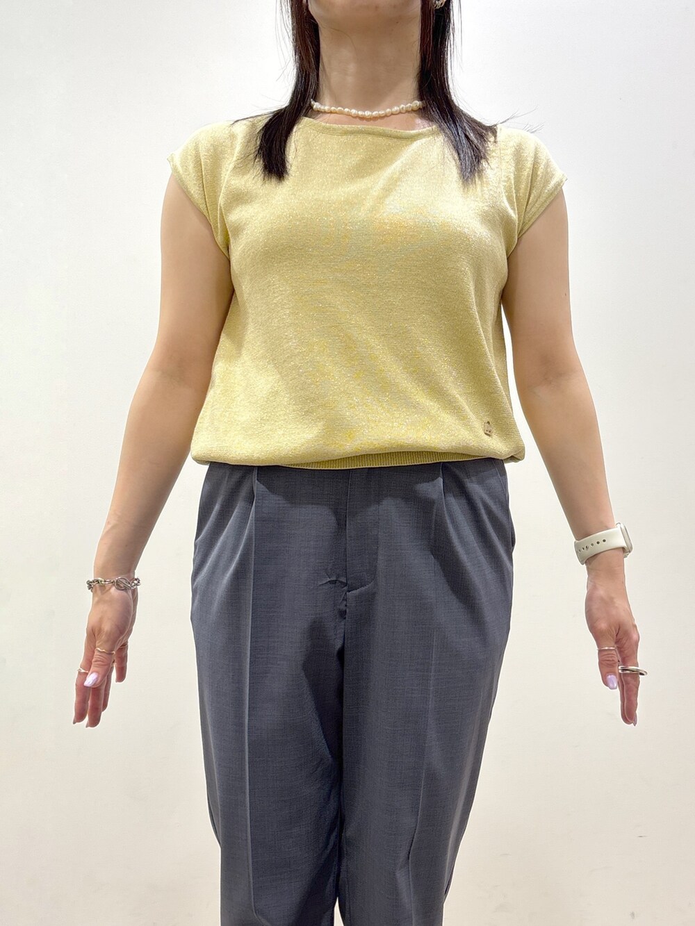 イエロー系のニット/セーター、グレー系のその他パンツ、ブラック系のトートバッグを着用したレディースの夏コーディネートの7枚目の写真