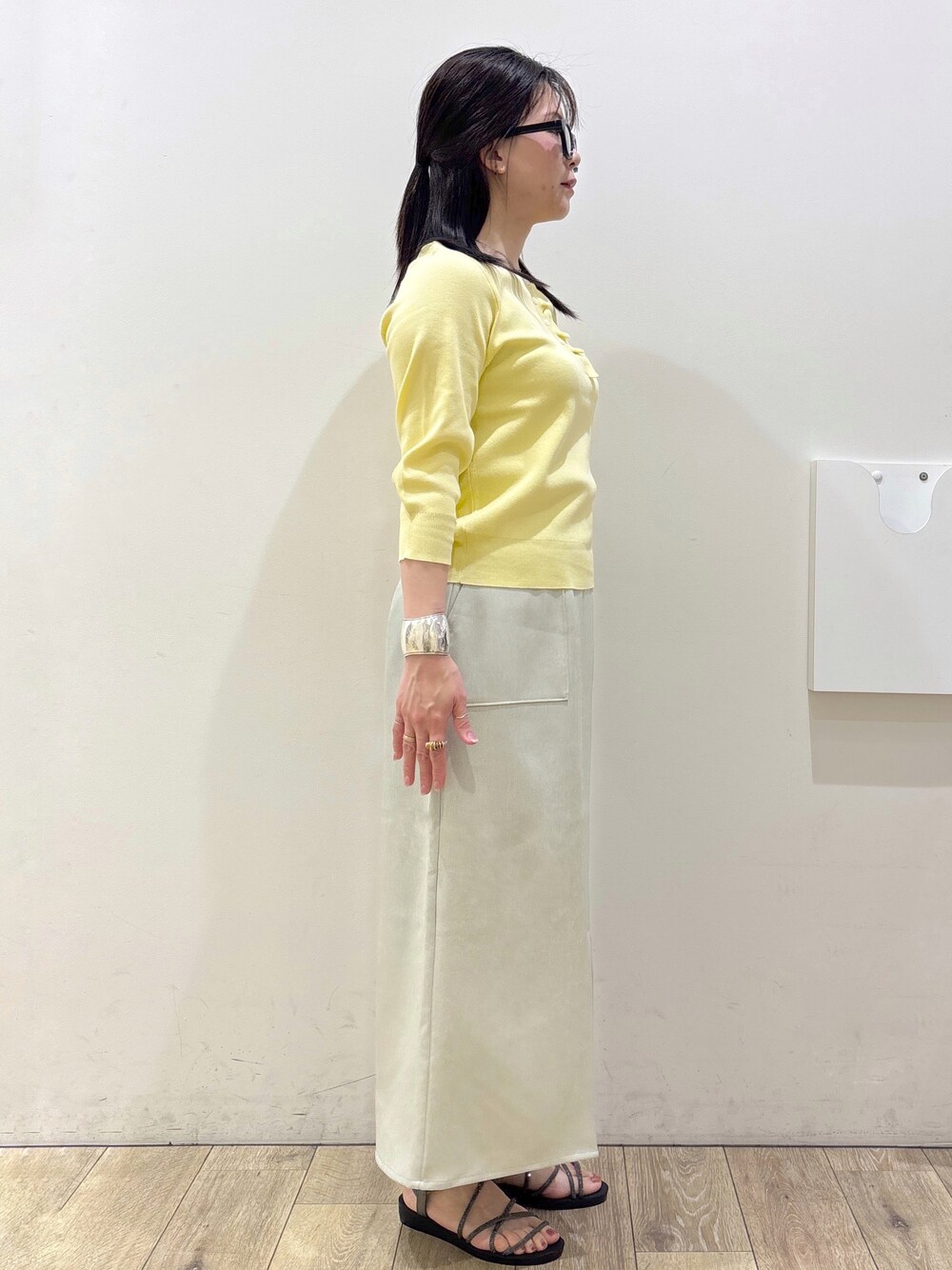 イエロー系のニット/セーター、ベージュ系のスカート、ホワイト系のトートバッグを着用したレディースの春コーディネートの7枚目の写真