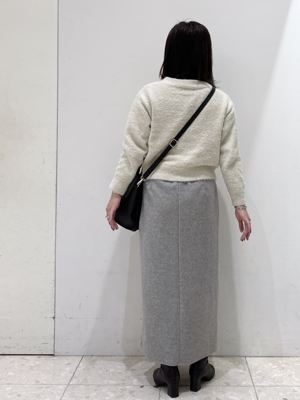ベージュ系のニット/セーター、グレー系のスカート、ブラック系のショルダーバッグを着用したレディースの冬コーディネートの3枚目の写真