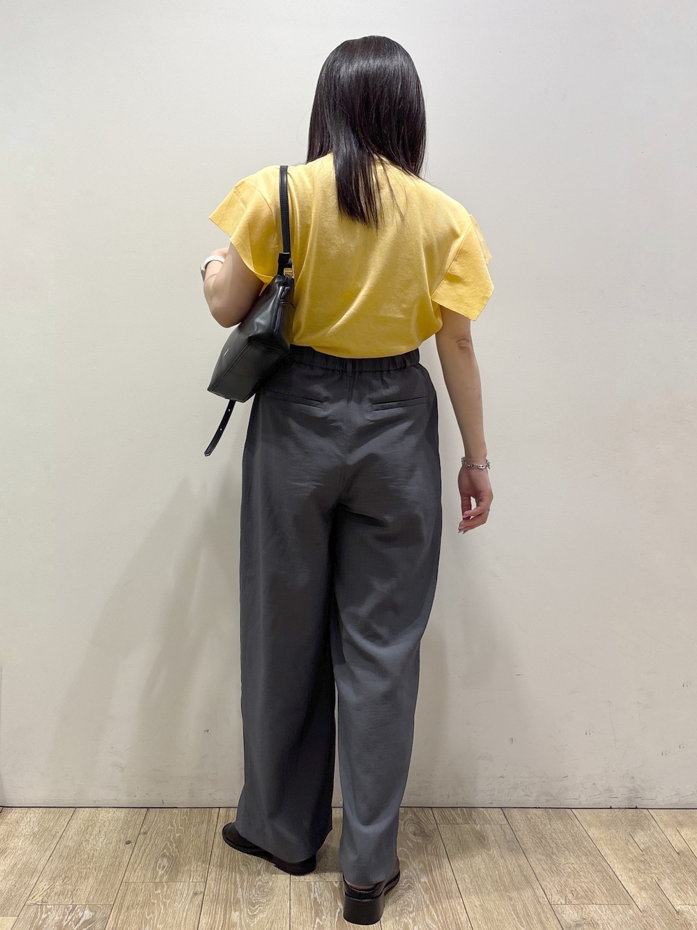 イエロー系のニット/セーター、グレー系のその他パンツ、ブラック系のショルダーバッグを着用したレディースの夏コーディネートの3枚目の写真