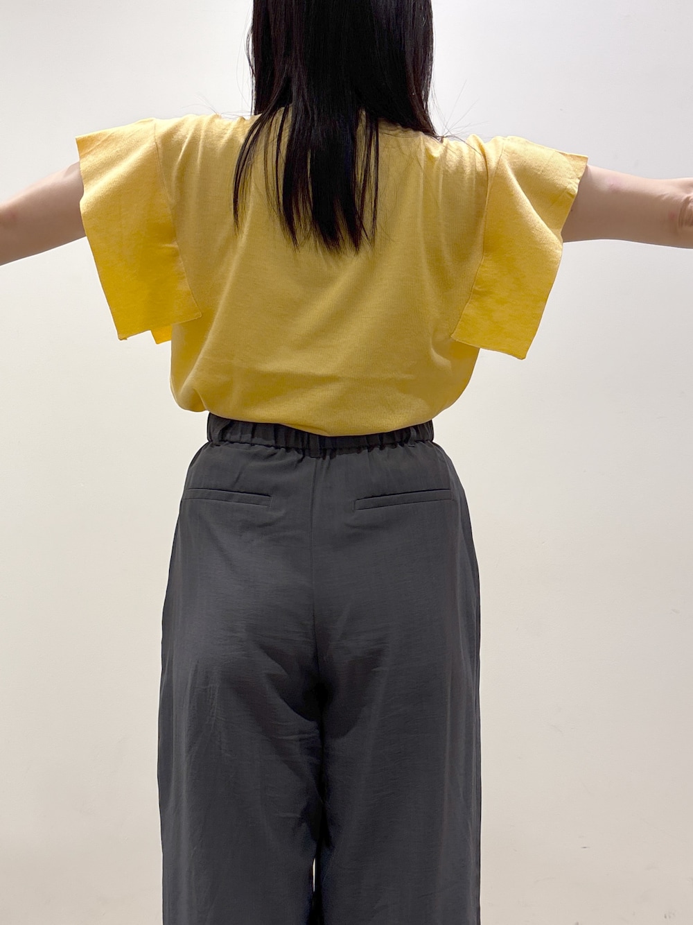 イエロー系のニット/セーター、グレー系のその他パンツ、ブラック系のショルダーバッグを着用したレディースの夏コーディネートの9枚目の写真