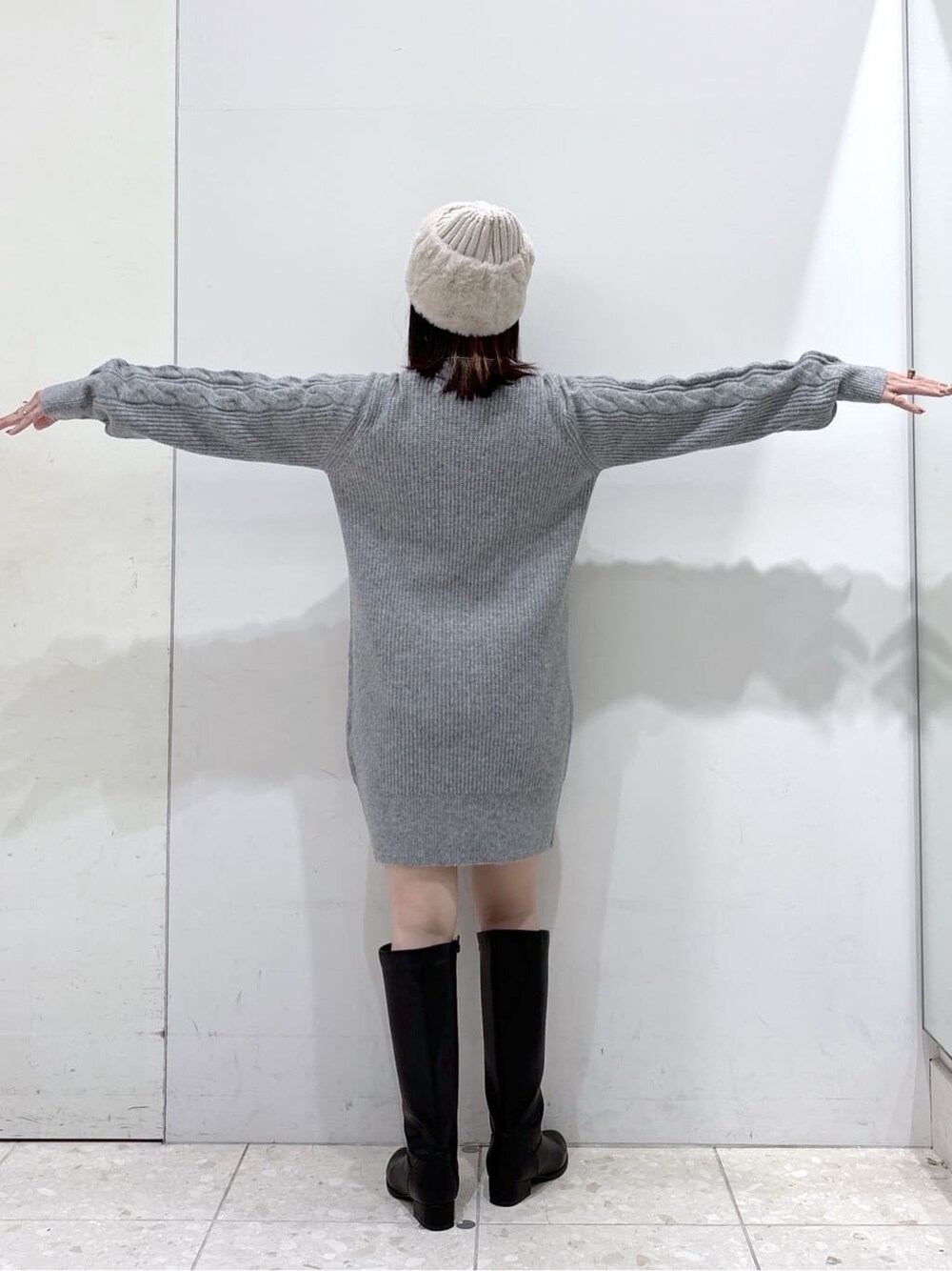 グレー系のワンピース、ブラック系のハンドバッグ、ブラック系のブーツを着用したレディースの冬コーディネートの5枚目の写真