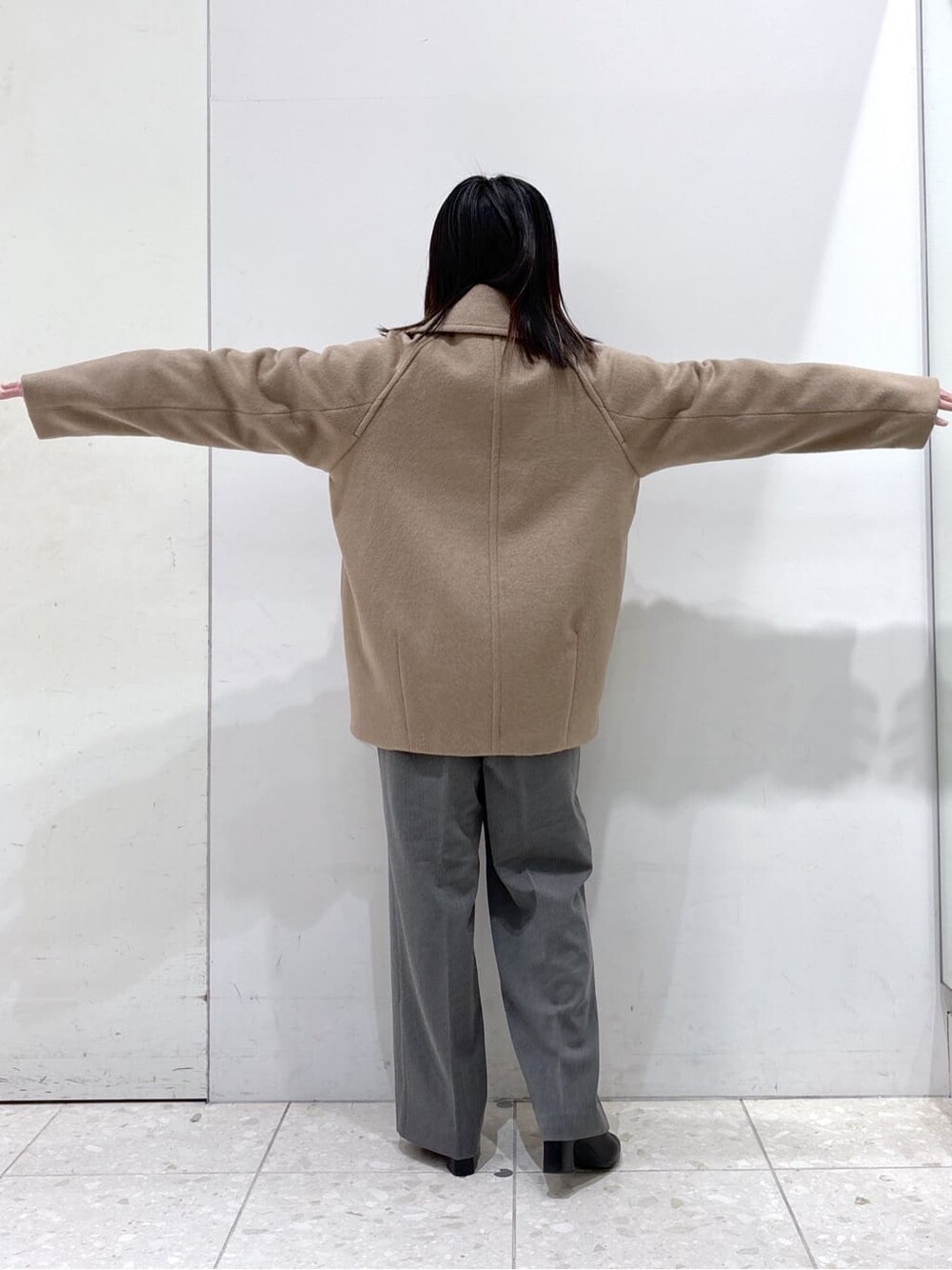 ベージュ系のピーコート、ブルー系のニット/セーター、グレー系のその他パンツを着用したレディースの冬コーディネートの3枚目の写真