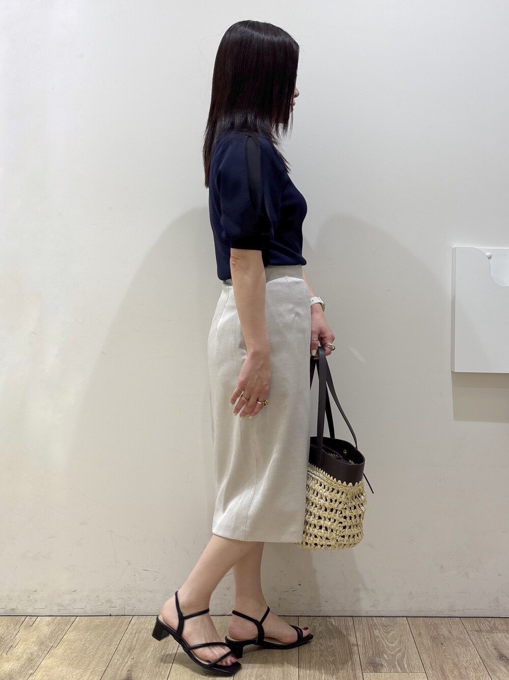ブルー系のニット/セーター、ベージュ系のスカート、ブラウン系のトートバッグを着用したレディースの夏コーディネートの2枚目の写真