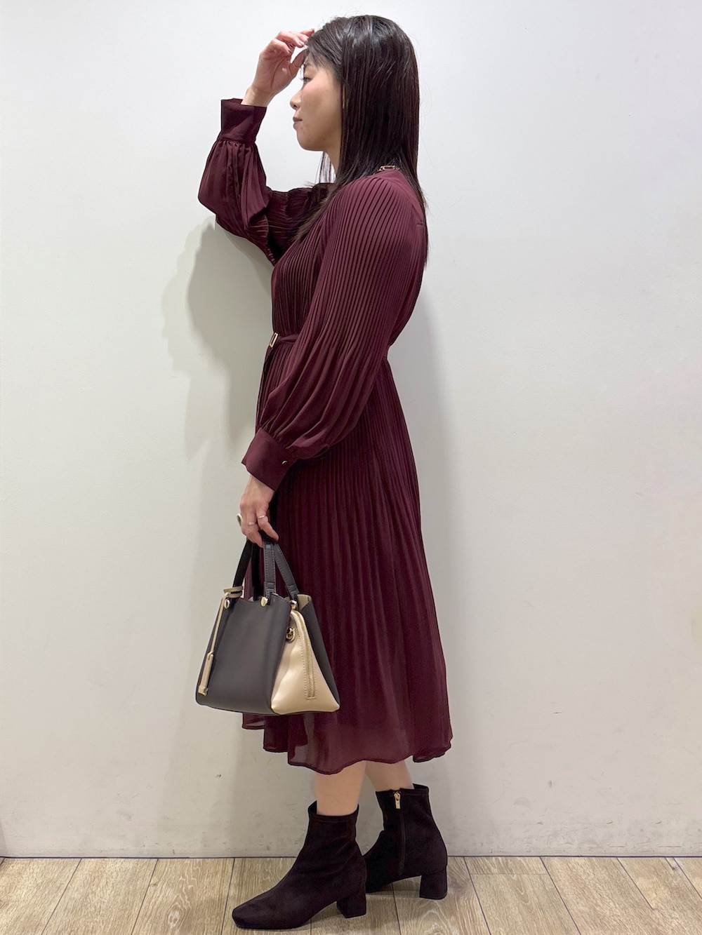 レッド系のワンピース、ブラウン系のボストンバッグ、ブラウン系のブーツを着用したレディースの秋コーディネートの4枚目の写真