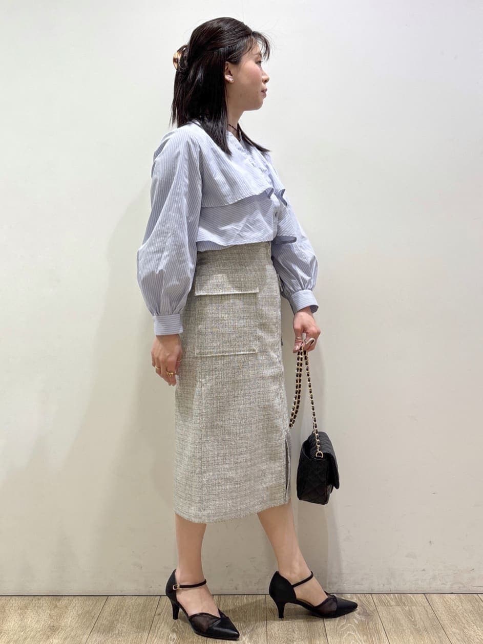 ブラック系のパンプス、ベージュ系のスカート、ブルー系のシャツ/ブラウスを着用したレディースの春コーディネートの2枚目の写真