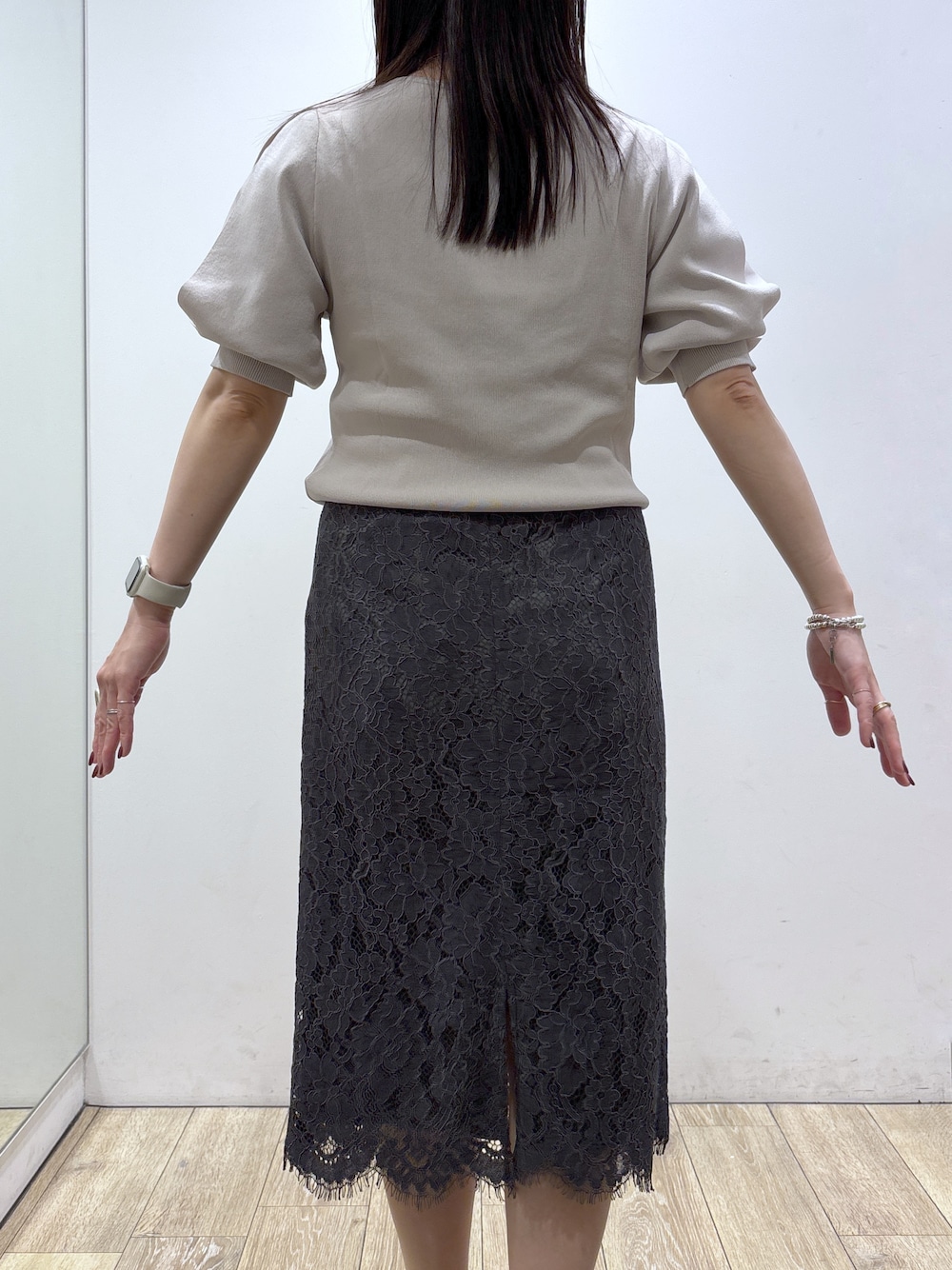 ベージュ系のニット/セーター、グレー系のスカート、ブラック系のトートバッグを着用したレディースの夏コーディネートの7枚目の写真