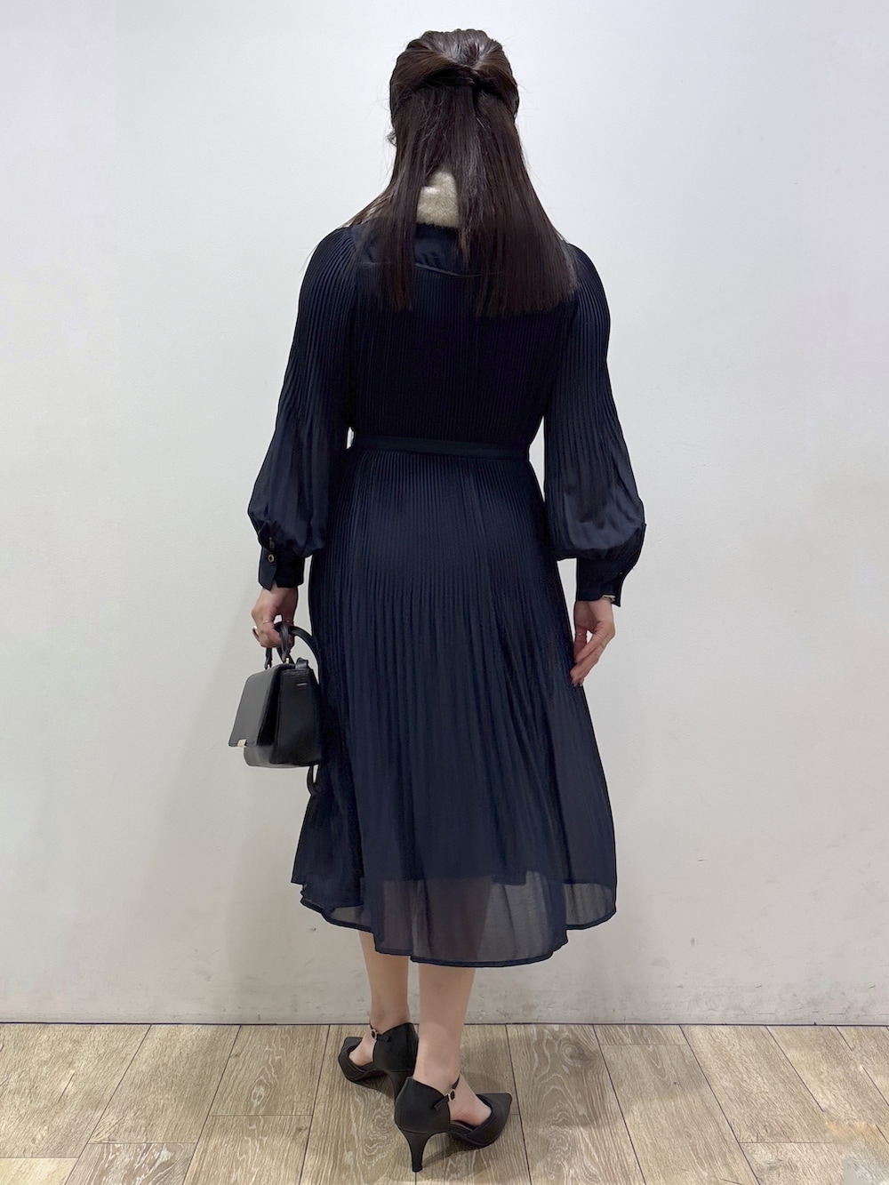 ブルー系のワンピース、ブラック系のショルダーバッグ、ブラック系のパンプスを着用したレディースの秋コーディネートの3枚目の写真