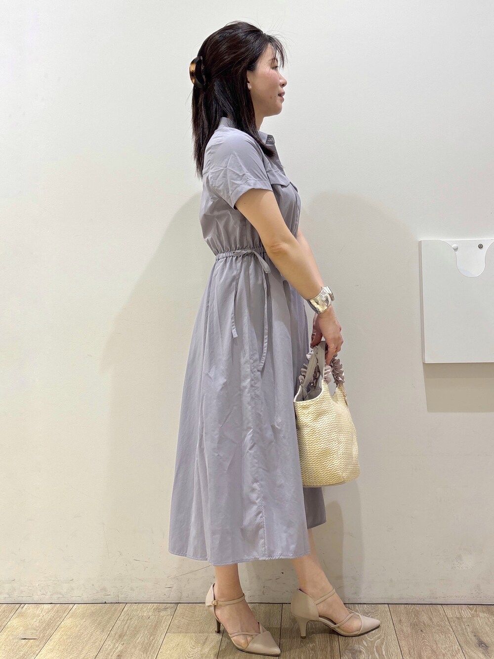 グレー系のワンピース、ベージュ系のトートバッグ、ベージュ系のパンプスを着用したレディースの春コーディネートの2枚目の写真