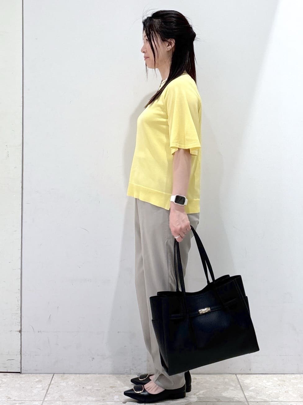 イエロー系のニット/セーター、ブラウン系のその他パンツ、ブラック系のトートバッグを着用したレディースの夏コーディネートの4枚目の写真