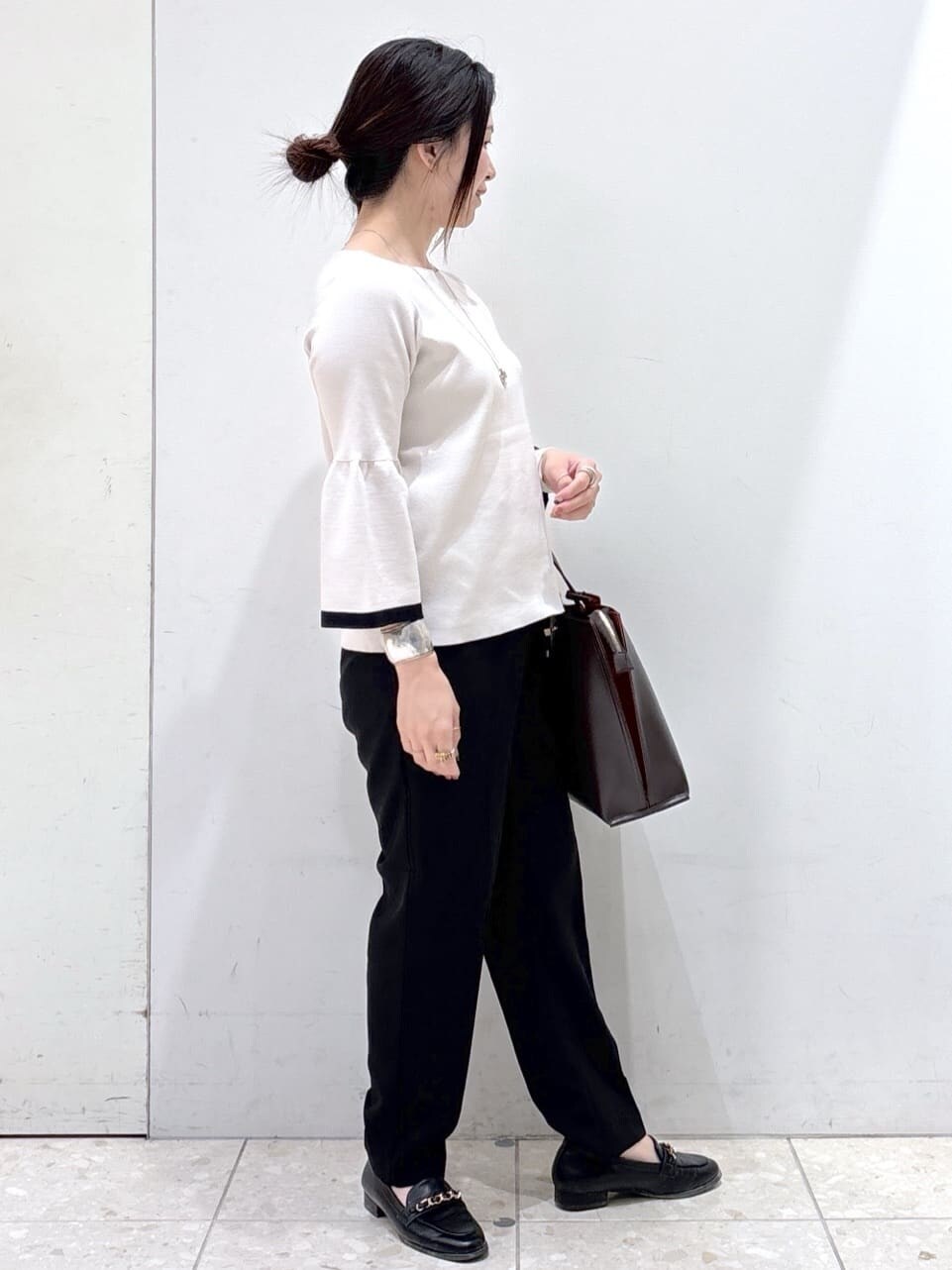 グレー系のニット/セーター、ブラック系のその他パンツ、ブラウン系のトートバッグを着用したレディースの秋コーディネートの2枚目の写真