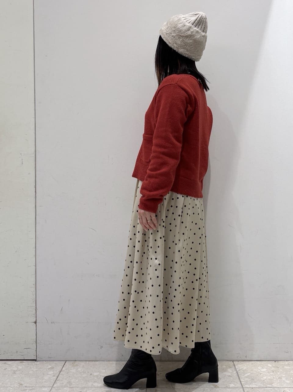 レッド系のカーディガン/ボレロ、ベージュ系のスカート、ベージュ系のトートバッグを着用したレディースの冬コーディネートの4枚目の写真