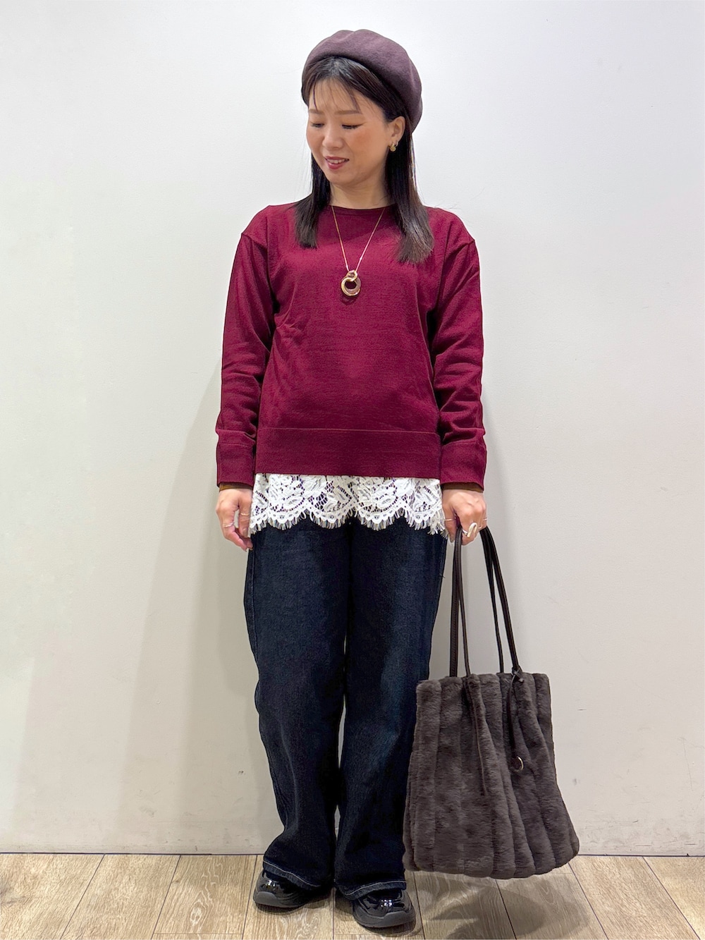 ブラウン系のノーカラーコート、レッド系のニット/セーター、ホワイト系のTシャツ/カットソーを着用したレディースの秋コーディネートの3枚目の写真