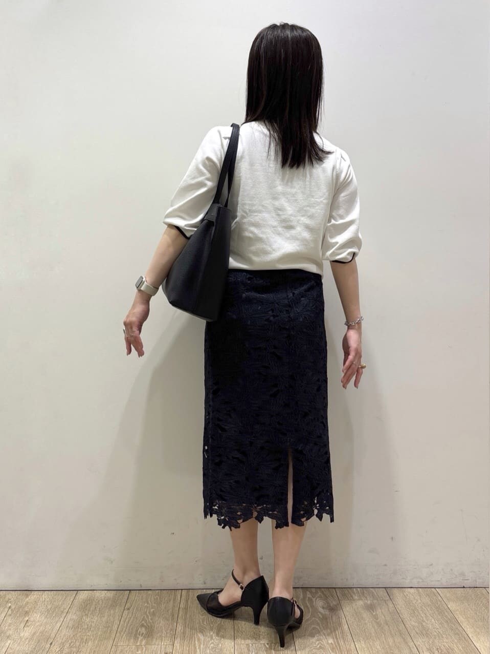 ブルー系のスカート、ブラック系のパンプス、ブラック系のトートバッグを着用したレディースの春コーディネートの8枚目の写真