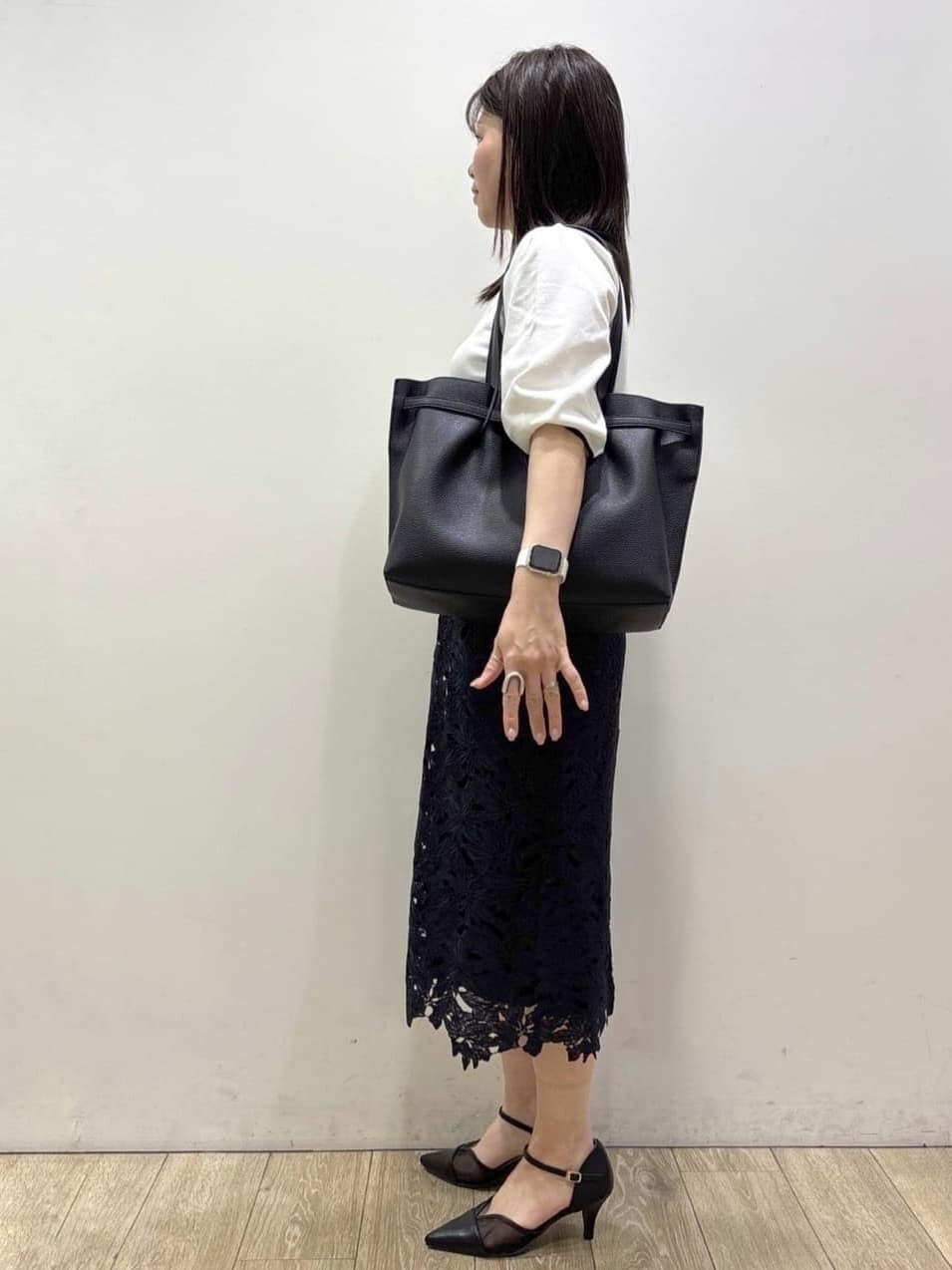 ブルー系のスカート、ブラック系のパンプス、ブラック系のトートバッグを着用したレディースの春コーディネートの2枚目の写真