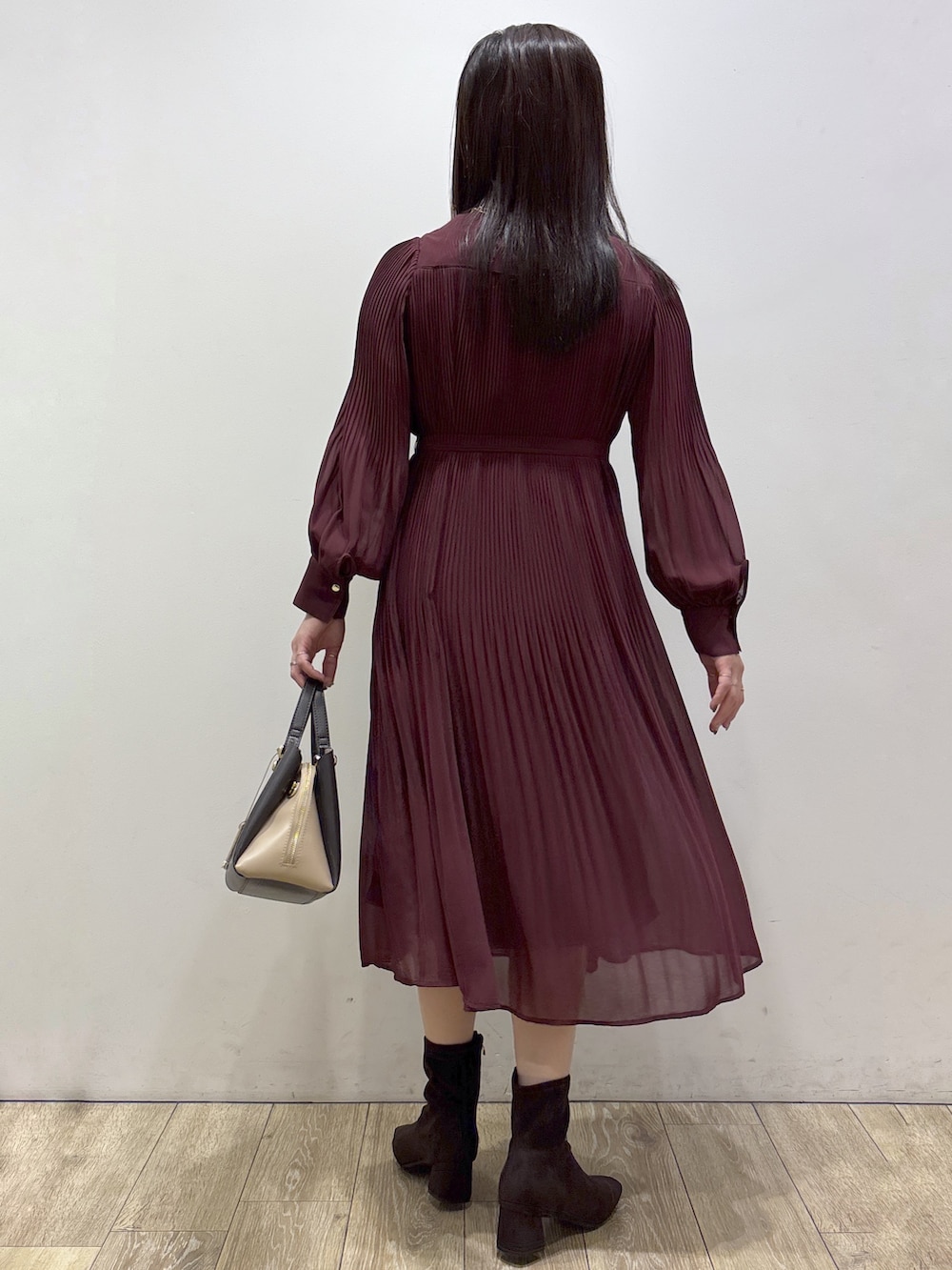 レッド系のワンピース、ブラウン系のボストンバッグ、ブラウン系のブーツを着用したレディースの秋コーディネートの3枚目の写真