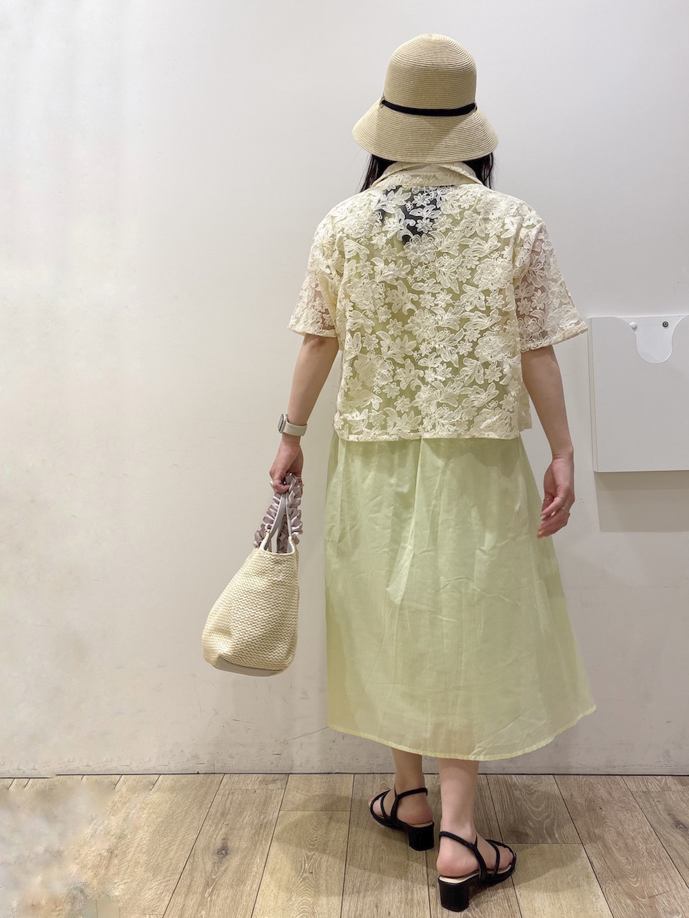 イエロー系のワンピース、ベージュ系のトートバッグ、ブラック系のサンダルを着用したレディースの夏コーディネートの3枚目の写真