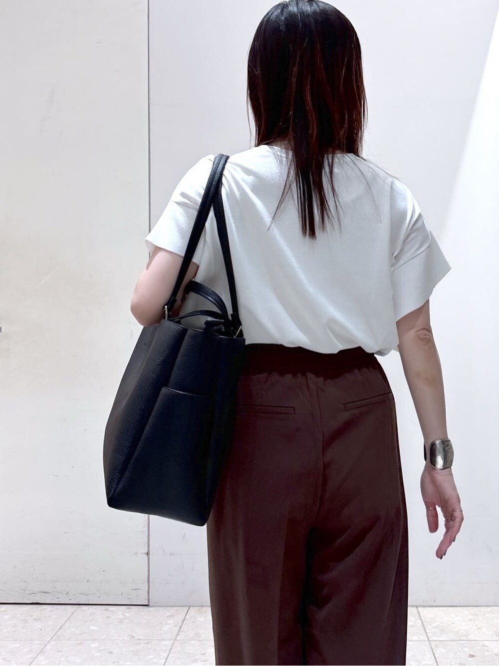 ホワイト系のニット/セーター、ブラウン系のその他パンツ、ブラック系のトートバッグを着用したレディースの夏コーディネートの4枚目の写真