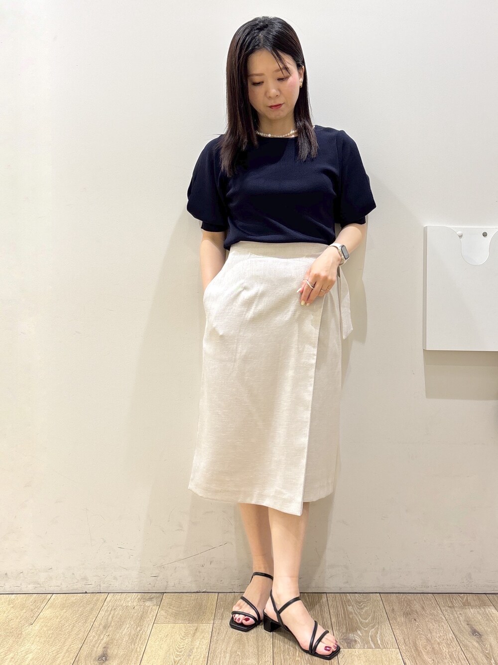 ブルー系のニット/セーター、ベージュ系のスカート、ブラウン系のトートバッグを着用したレディースの夏コーディネートの5枚目の写真