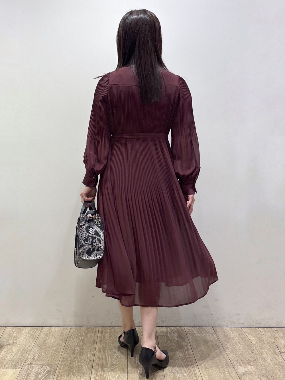 レッド系のワンピース、ブラック系のトートバッグ、ブラック系のパンプスを着用したレディースの秋コーディネートの3枚目の写真