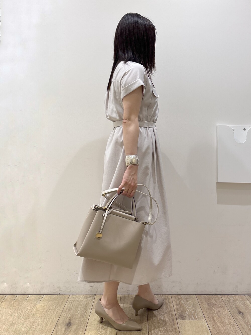 ベージュ系のワンピース、ベージュ系のトートバッグ、ベージュ系のパンプスを着用したレディースの夏コーディネートの3枚目の写真