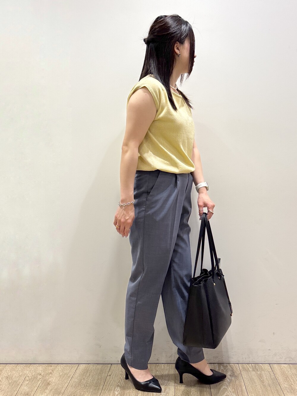 イエロー系のニット/セーター、グレー系のその他パンツ、ブラック系のトートバッグを着用したレディースの夏コーディネートの3枚目の写真