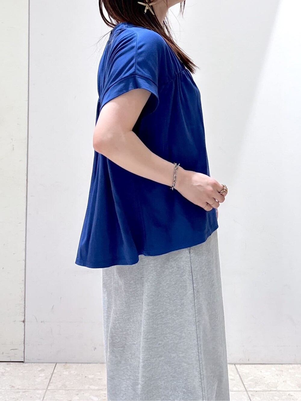 ブルー系のTシャツ/カットソー、グレー系のスカート、ブラック系のトートバッグを着用したレディースの夏コーディネートの6枚目の写真
