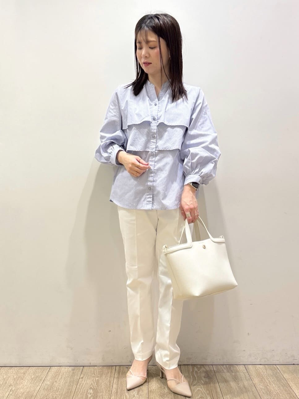 ベージュ系のパンプス、ブルー系のシャツ/ブラウス、ホワイト系のショルダーバッグを着用したレディースの春コーディネートの6枚目の写真