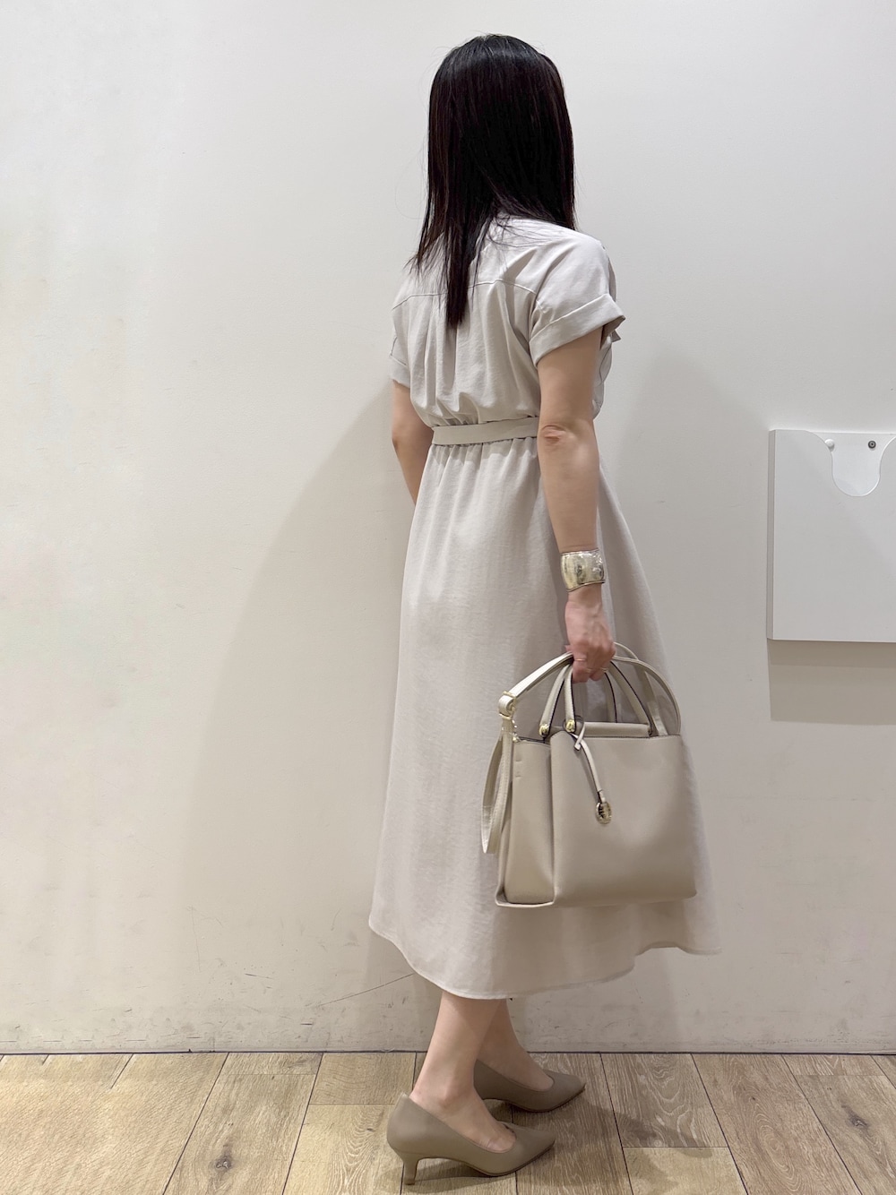 ベージュ系のワンピース、ベージュ系のトートバッグ、ベージュ系のパンプスを着用したレディースの夏コーディネートの2枚目の写真