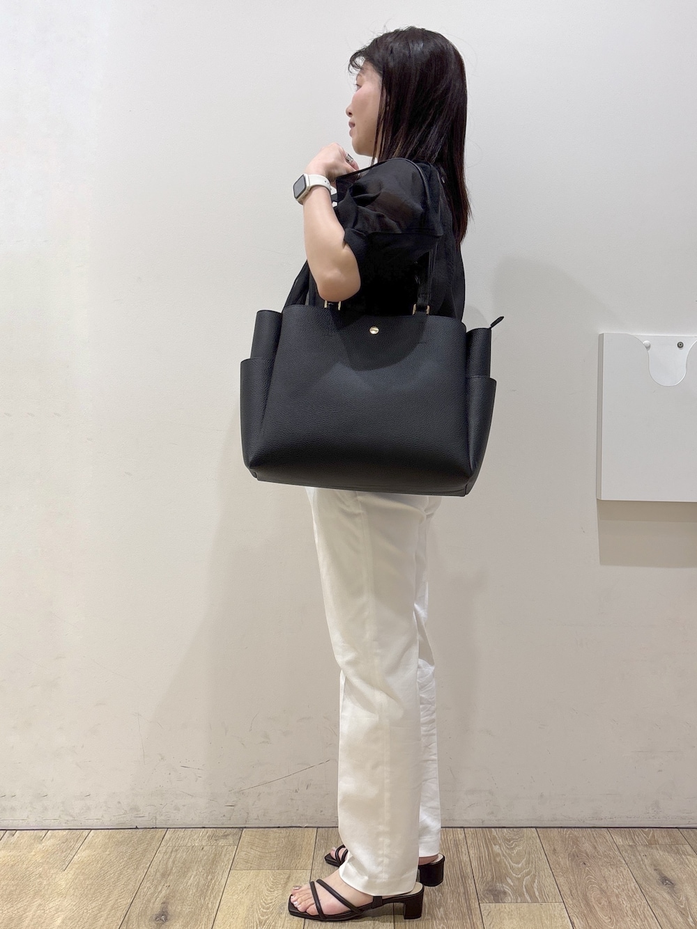 ブラック系のトートバッグ、ブラウン系のサンダル、ホワイト系のその他パンツを着用したレディースの春コーディネートの2枚目の写真