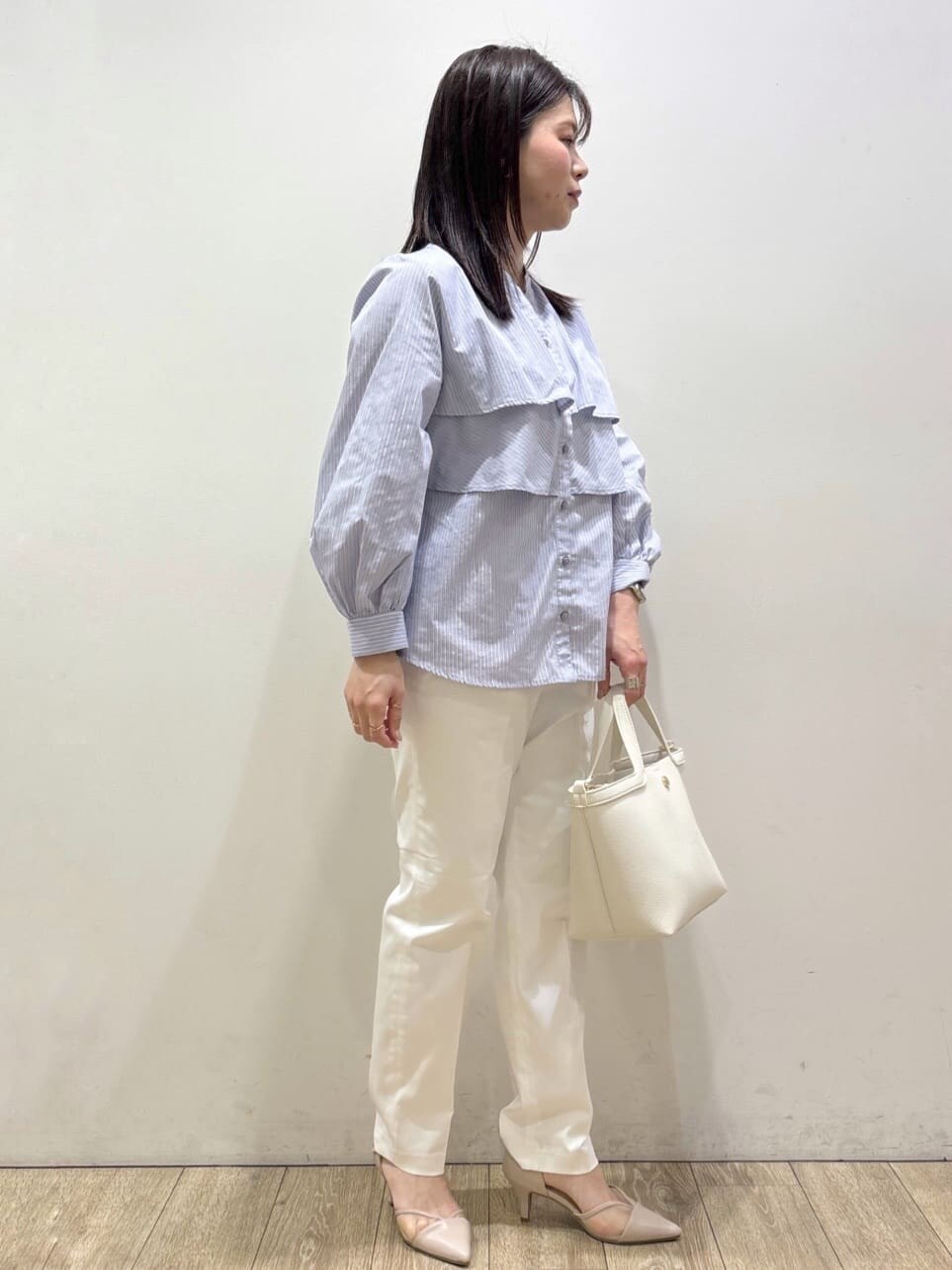 ベージュ系のパンプス、ブルー系のシャツ/ブラウス、ホワイト系のショルダーバッグを着用したレディースの春コーディネートの2枚目の写真