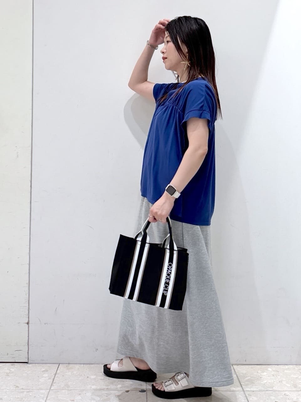 ブルー系のTシャツ/カットソー、グレー系のスカート、ブラック系のトートバッグを着用したレディースの夏コーディネートの4枚目の写真