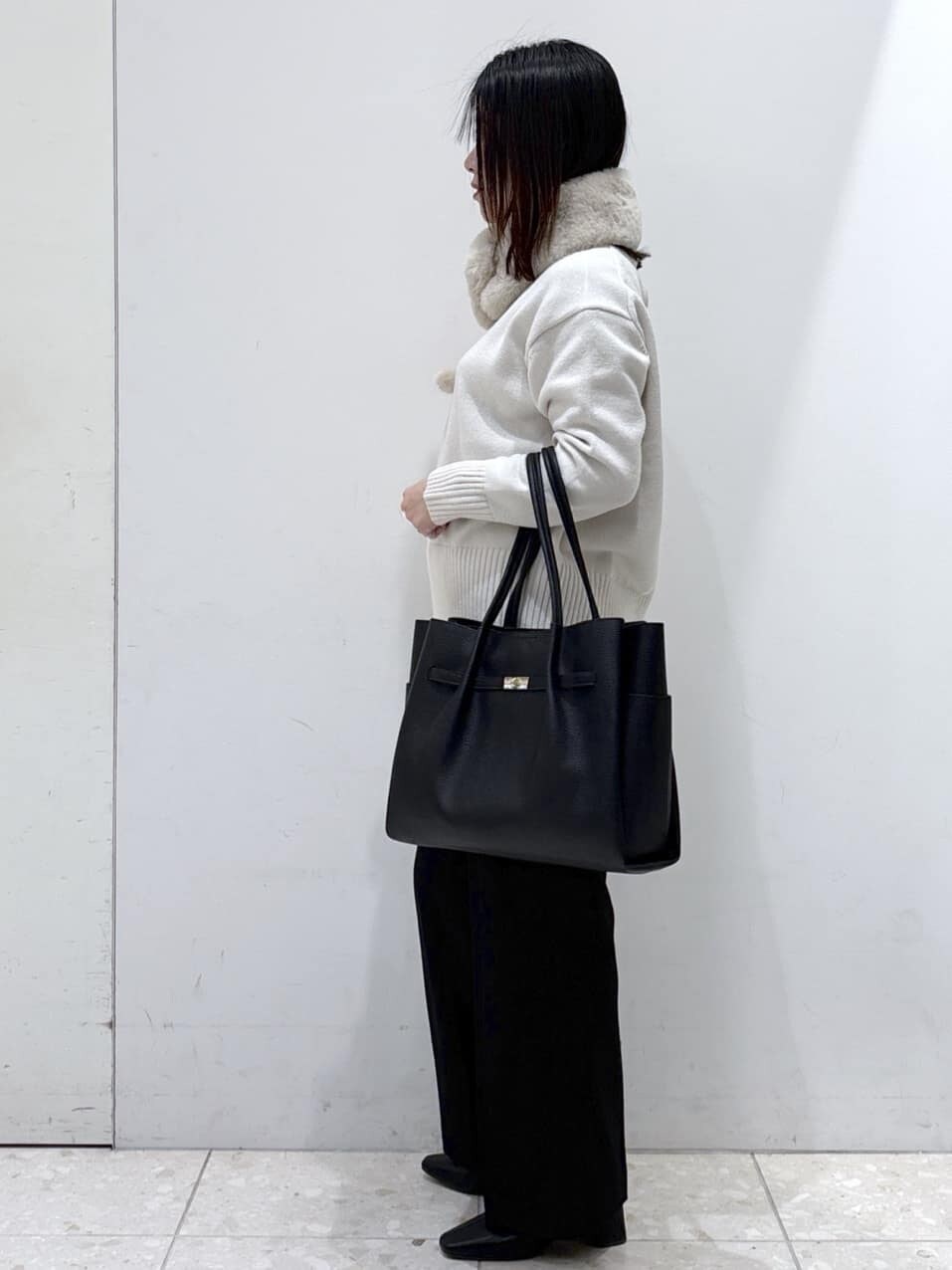 ホワイト系のニット/セーター、ブラック系のその他パンツ、ブラック系のトートバッグを着用したレディースの冬コーディネートの2枚目の写真