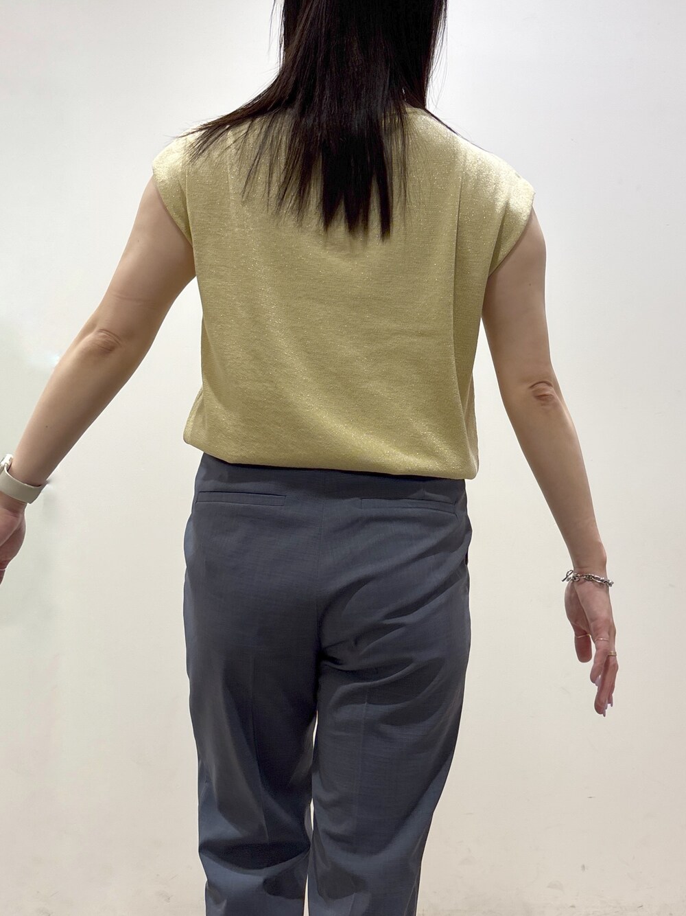 イエロー系のニット/セーター、グレー系のその他パンツ、ブラック系のトートバッグを着用したレディースの夏コーディネートの9枚目の写真