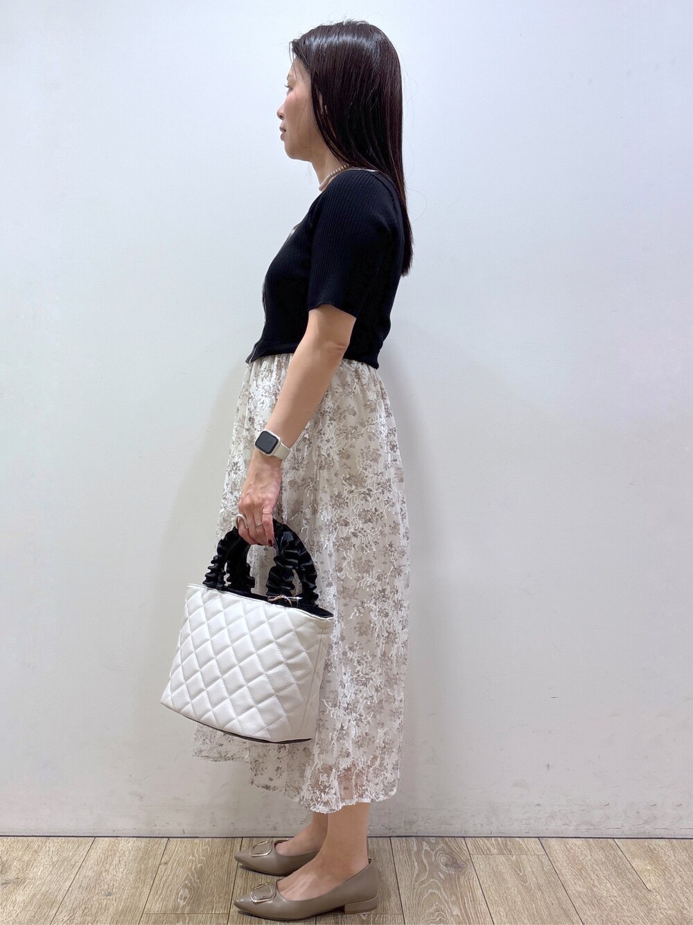 ブラック系のワンピース、ホワイト系のショルダーバッグ、ベージュ系のパンプスを着用したレディースの夏コーディネートの4枚目の写真