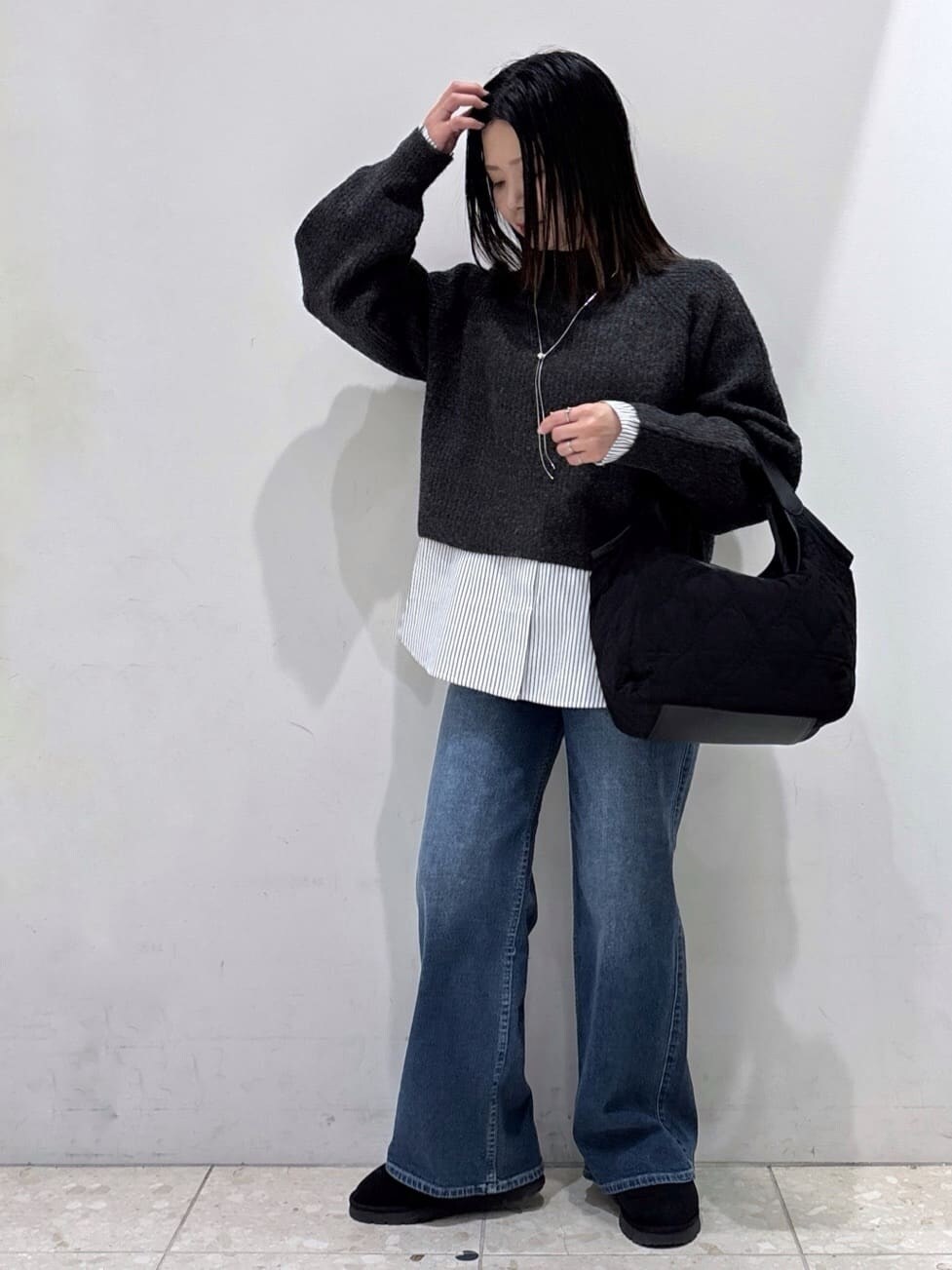 グレー系のニット/セーター、ホワイト系のTシャツ/カットソー、ブルー系のデニムパンツを着用したレディースの冬コーディネートの5枚目の写真