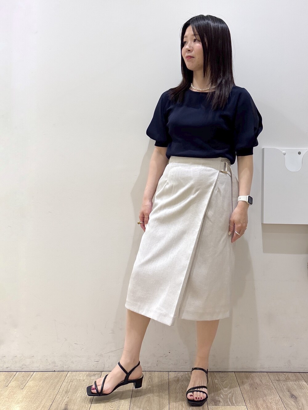 ブルー系のニット/セーター、ベージュ系のスカート、ブラウン系のトートバッグを着用したレディースの夏コーディネートの7枚目の写真