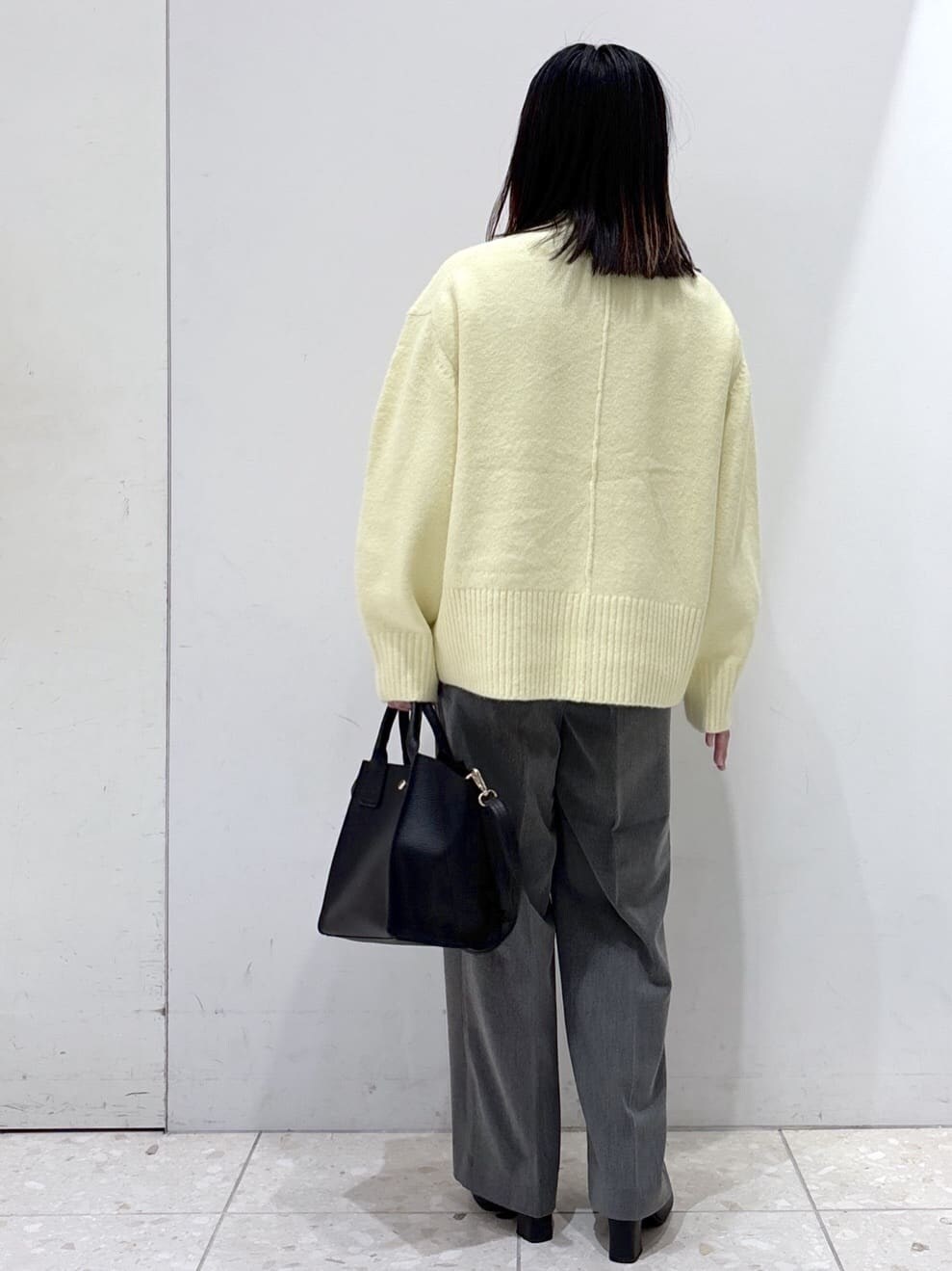 イエロー系のニット/セーター、グレー系のその他パンツ、ブラック系のショルダーバッグを着用したレディースの冬コーディネートの3枚目の写真