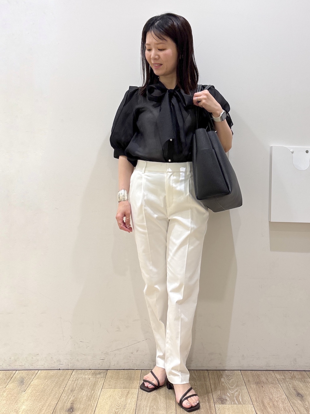 ブラック系のトートバッグ、ブラウン系のサンダル、ホワイト系のその他パンツを着用したレディースの春コーディネートの7枚目の写真