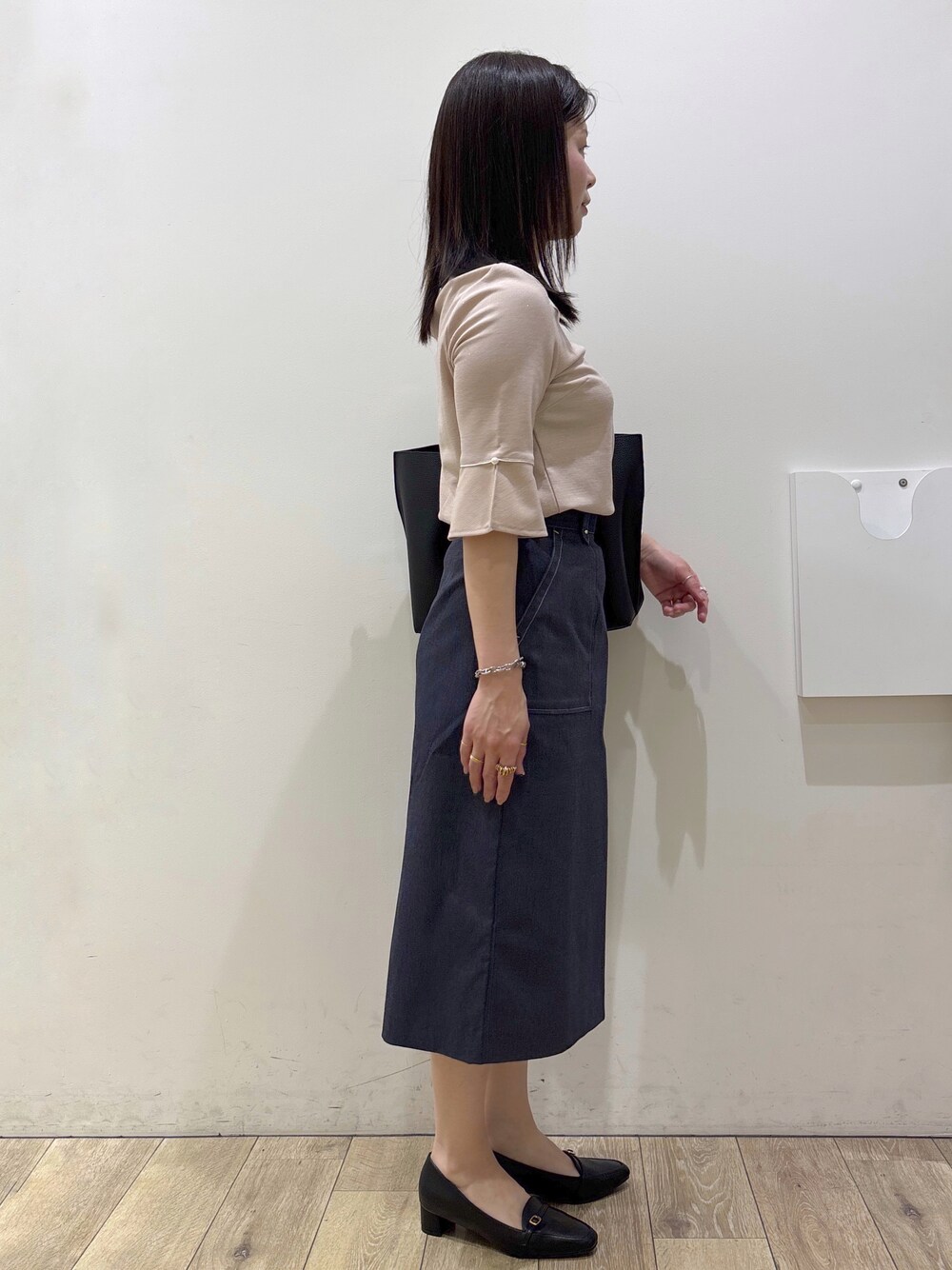 ブラック系のパンプス、ブラック系のトートバッグ、ブルー系のスカートを着用したレディースの春コーディネートの2枚目の写真
