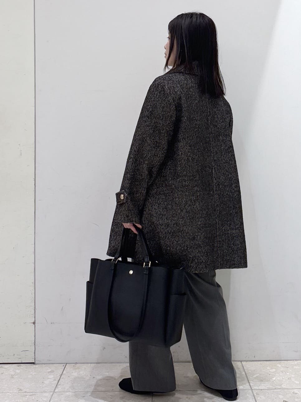 ブラック系のステンカラーコート、ホワイト系のニット/セーター、グレー系のその他パンツを着用したレディースの冬コーディネートの4枚目の写真
