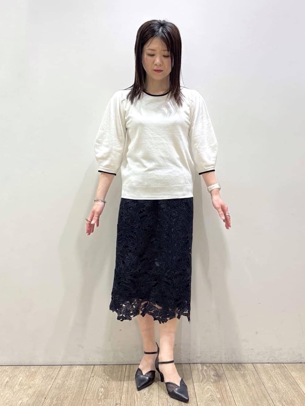 ブルー系のスカート、ブラック系のパンプス、ブラック系のトートバッグを着用したレディースの春コーディネートの7枚目の写真